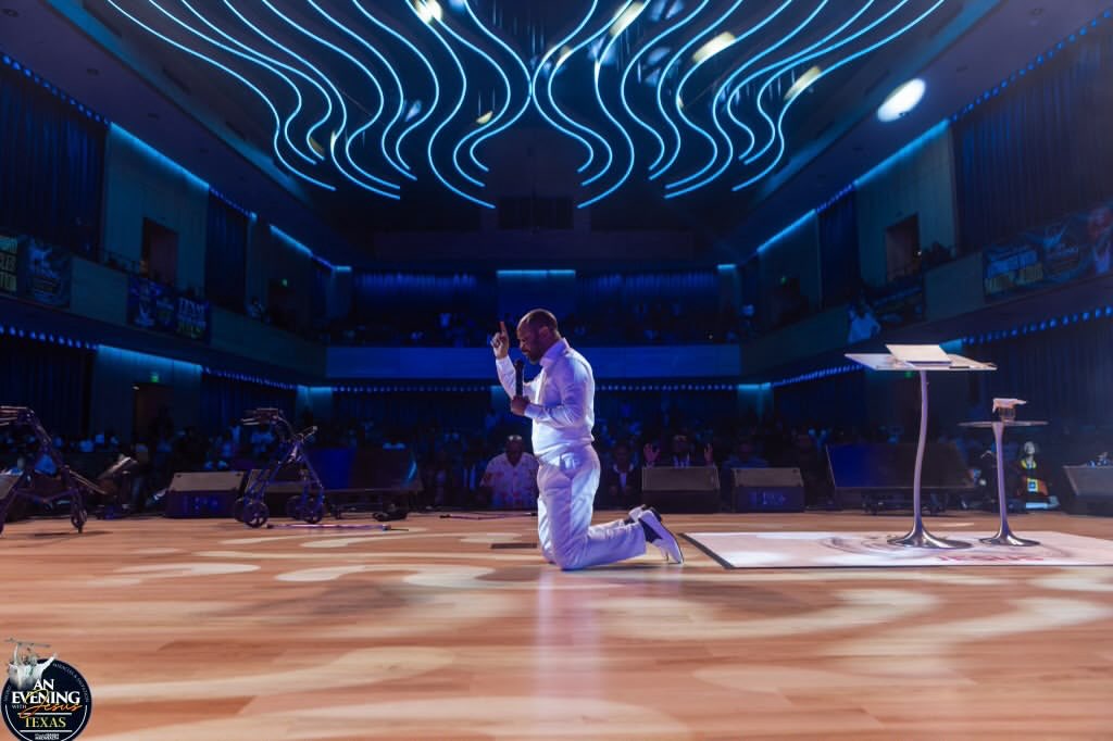 Prophet Isaiah Macwealth kneeling in prayer on stage at An Evening With Jesus, Texas